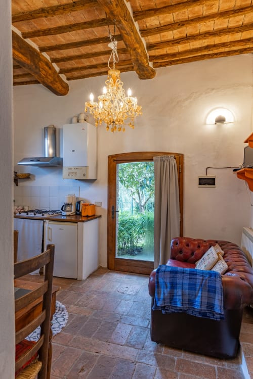 Accogliente appartamento a Buonconvento con travi a vista, angolo cottura, divano in pelle, lampadario e vista sul giardino