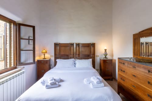 Camera luminosa con letto in legno e arredi, biancheria bianca, illuminazione calda all'hotel Quarantallina a Buonconvento, Italia