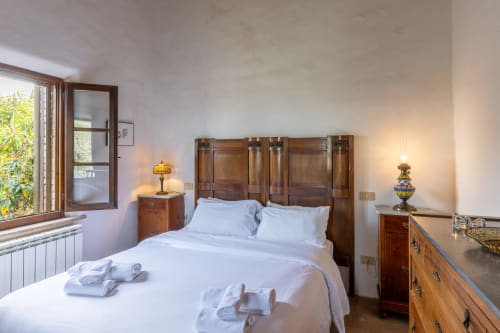 Camera luminosa con letto in legno e arredi, finestra con vista sul giardino presso l'hotel Quarantallina a Buonconvento, Italia