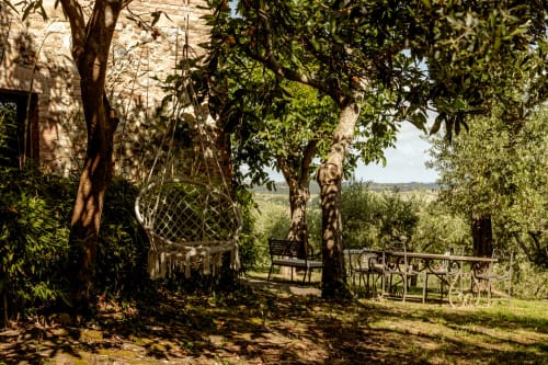 Terrazza giardino ombreggiata con altalena sospesa, mobili in legno e vista sulla campagna dell'hotel Buonconvento