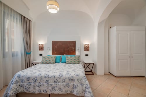 Camera da letto moderna e luminosa di Short Let's Olbia con accenti turchesi, soffitto a volta e pavimentazione in cotto, Olbia, Italia.
