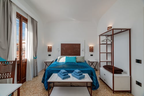 Camera moderna di Short Let's Olbia con biancheria blu, letto a baldacchino in legno, pareti bianche e pavimento in cotto a Olbia, Italia