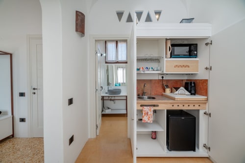 Piccola cucina moderna di Short Let's Olbia con mobili bianchi, piani in legno e elettrodomestici compatti in stile italiano
