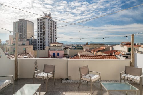 Terrazza sul tetto di Short Let's Olbia con sdraio che si affacciano sul panorama della città e sulle montagne