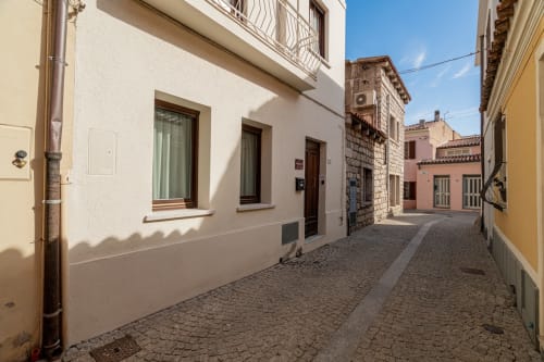 Affascinante vicolo di ciottoli presso l'hotel Short Let's Olbia con edifici mediterranei imbiancati e persiane verdi