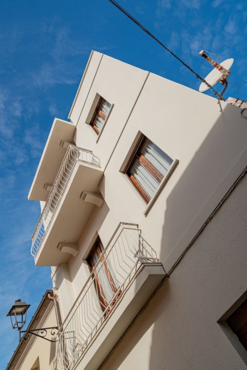 Facciata di moderno edificio bianco a Olbia con antenna parabolica e balconate contro il cielo blu