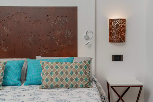Camera da letto a tema costiero presso Short Let's Olbia con cuscini turchesi, testata letto con bassorilievo di vita marina e decorazioni a forma di stella marina