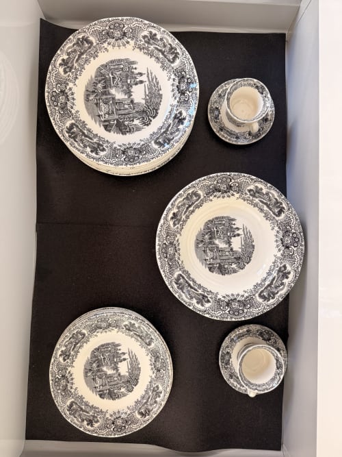 Vajilla decorativa en blanco y negro con bordes ornamentados y diseño central con paisaje, exhibida en suite del hotel Sevilla