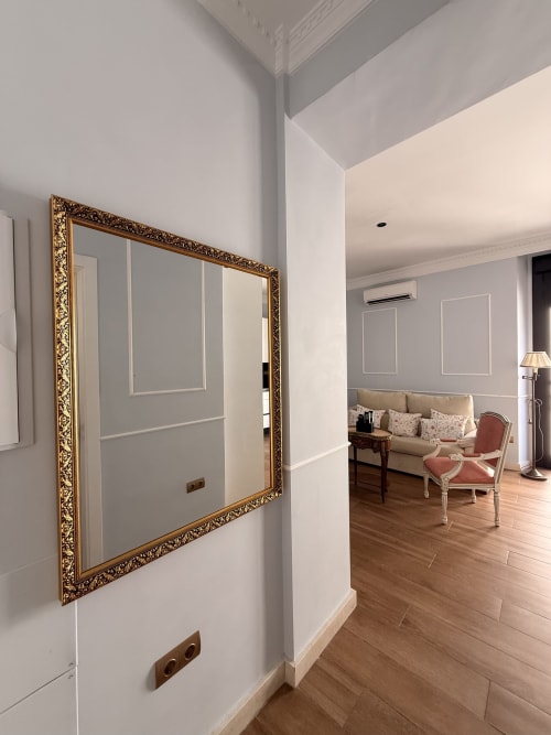 Elegante pasillo de suite hotelera sevillana con espejo de marco dorado ornamentado, suelos de madera y vista parcial de la sala de estar