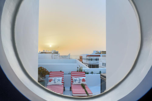 Lettini rossi e bianchi a righe su una terrazza con vista sulla spiaggia di El Cotillo al tramonto, El Patrón Casa de Huéspedes