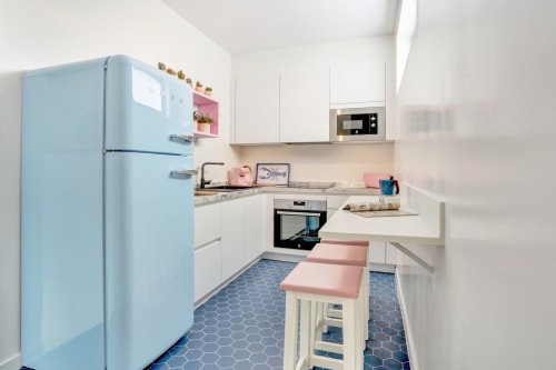 Moderna cucina rustica con frigorifero azzurro retrò, mobili bianchi e dettagli rosa presso El Patrón Casa de Huéspedes