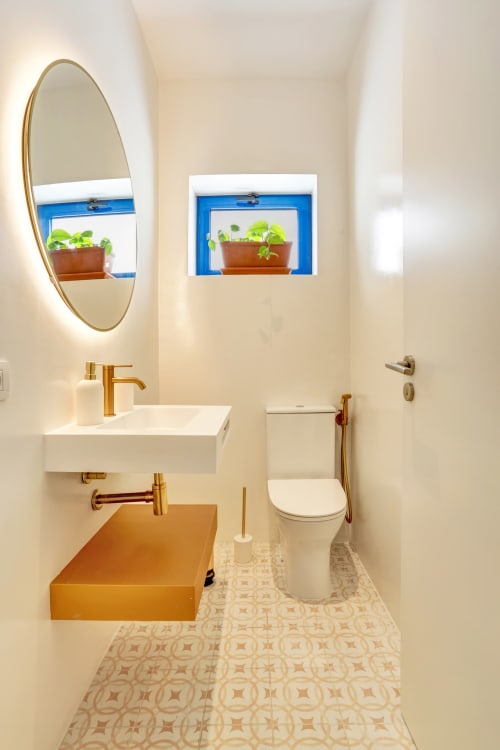 Bagno moderno nel cottage El Patrón a El Cotillo con finiture dorate, specchio rotondo e erbe aromatiche sul davanzale