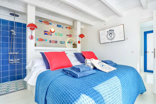 Luminosa camera da letto con biancheria blu, cuscini rossi e arredamento nautico presso El Patrón Casa de Huéspedes a El Cotillo