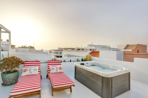 Terrazza panoramica di El Patrón Casa de Huéspedes a El Cotillo con lettini a righe rosse, vasca idromassaggio e vista sul mare
