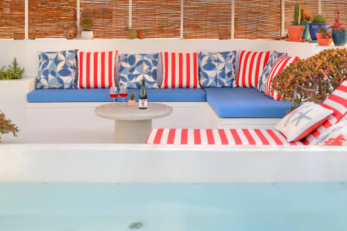 Patio della casa costiera con divano componibile blu, cuscini a righe rosso-bianche e vista sulla piscina di El Patrón Casa de Huéspedes