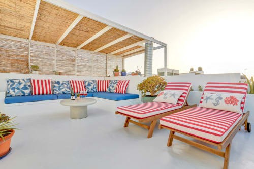 Terrazza panoramica di El Patrón Casa de Huéspedes con lettini rigati, sedute blu e vista mare a El Cotillo