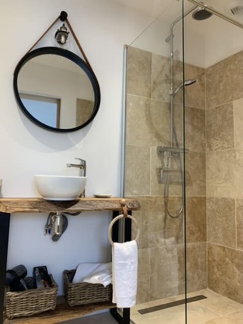 Salle de bains moderne en maison provençale de la Drôme avec miroir rond, vasque, meuble en bois et douche ouverte