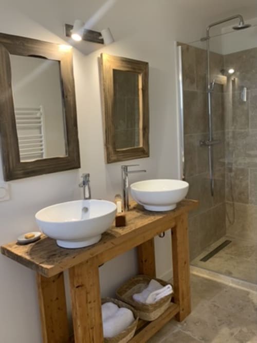 Salle de bain moderne avec vasques blanches jumelées sur meuble en bois, miroirs encadrés, douche vitrée dans cottage de la Drôme