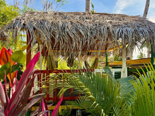 Abri palapa en chaume avec plantes tropicales colorées à l'hôtel Le Chissioua à Sada, YT