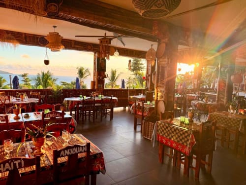 Le restaurant Le Chissioua à Sada : terrasse vue océan, décor en bois, nappes à motifs rouges au coucher du soleil