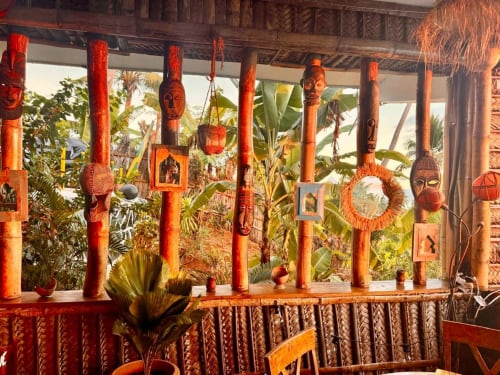 Des colonnes et masques d'inspiration tribale ornent l'intérieur de l'hôtel Le Chissioua à Sada, dominant les jardins tropicaux.