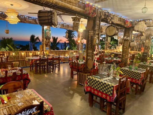 Le restaurant Chissioua avec vue sur l'océan, décoré d'éléments en bois traditionnel, de tissus colorés et de plantes à Sada