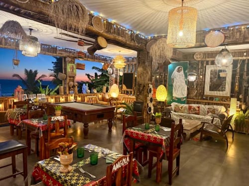 Le salon de l'hôtel Le Chissioua à Sada avec décor d'inspiration africaine, éclairage tressé, billard et vue sur le coucher de soleil océanique