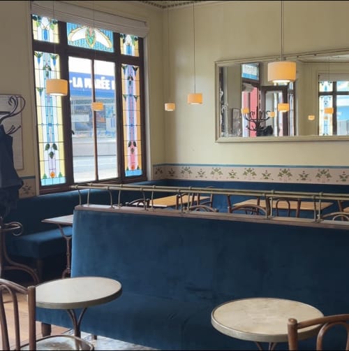 Intérieur Art Déco du café de l'hôtel Hidden Bay à Cayeux-sur-Mer avec portes en vitrail et sièges en velours bleu