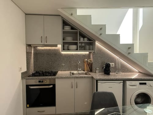 Modern compact kitchen with stainless steel appliances, gas stove, under-stair storage in Chaves apartment