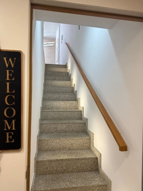 Stairwell with gray carpet and wooden handrail, welcome sign visible at Portuguese apartment entrance