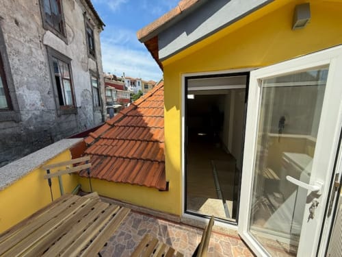 Charming hidden gem apartment balcony in Chaves with yellow walls, terracotta roofing, and French doors overlooking historic