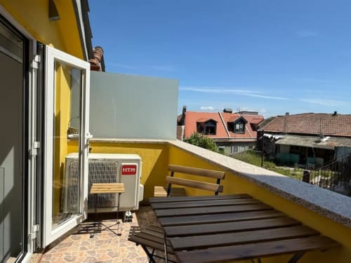 Sunny terrace at charming hidden gem apartment in Chaves, Portugal with yellow walls and lounge chairs