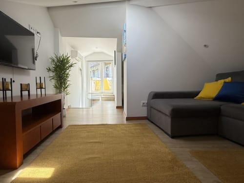 Modern apartment in Chaves with gray sofa, dining area, and natural light from balcony doors