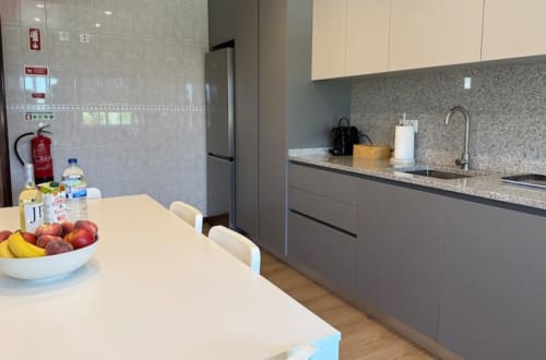 Modern kitchen and dining area in Chaves apartment with granite counters, gray cabinetry, and fresh fruit on table