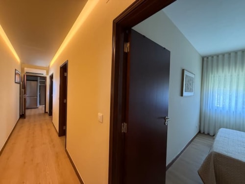 Modern apartment hallway in Chaves with warm lighting, dark doors, and wood flooring