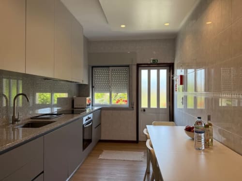 Modern kitchen with dining area in Chaves apartment near Porto, featuring stainless steel appliances and garden views