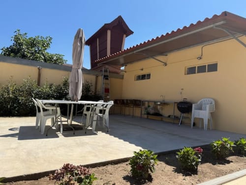 Yellow apartment patio with table, chairs, umbrella and grill at Voluta Management B&B in Chaves, Portugal