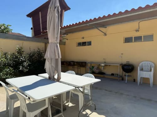 Outdoor patio area at Voluta Management BnB in Chaves with dining table, umbrella, and white chairs