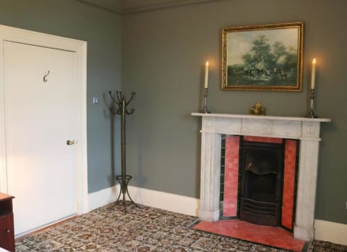 Salon élégant du South Hill House avec cheminée, manteau blanc, candélabres et œuvre paysagère