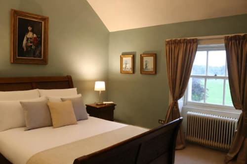 Chambre élégante du cottage South Hill House à Delvin, vue sur le jardin, lit en bois, murs vert sage et décoration traditionnelle