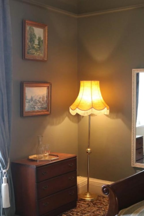 Chambre chaleureuse avec lampadaire, commode en bois, œuvres encadrées et mobilier d'époque à South Hill House, Delvin