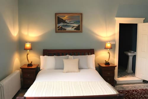 Chambre douillette du cottage South Hill House à Delvin avec literie blanche, tables de nuit en bois, lampes chaleureuses et décoration côtière.