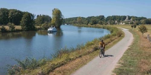 Cycliste sur un chemin de halage avec bateau amarré, campagne de Gorrevod en France