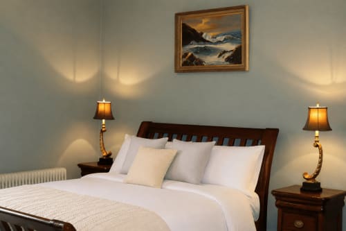 Chambre élégante de South Hill House avec lit en bois, draps blancs, lampes en laiton et tableau marin au-dessus de la tête de lit