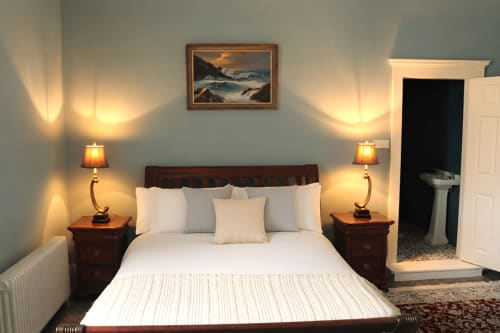 Chambre premium à South Hill House, Delvin avec lit queen, draps blancs, tables de nuit en bois, éclairage chaleureux et vue sur mer