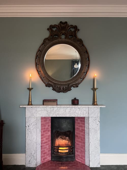 Miroir en bois sombre orné au-dessus d'une cheminée en marbre avec des bougies allumées à South Hill House, Delvin