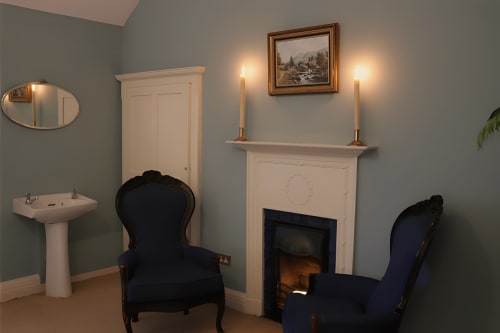 Élégant salon avec cheminée à South Hill House, Delvin, présentant des fauteuils en velours bleu et un éclairage chaleureux