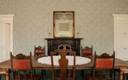Élégante salle à manger de South Hill House à Delvin avec cheminée, table ronde, chaises en cuir rouge et papier peint à motifs damassés
