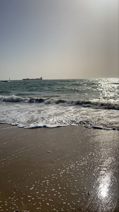 Escena soleada de playa con olas y arena cerca de Jerez de la Frontera, vista costera de G&H Apartments
