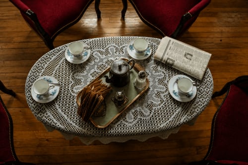 Vue aérienne d'un élégant service à thé à South Hill House avec tasses, théière et journal sur nappe en dentelle